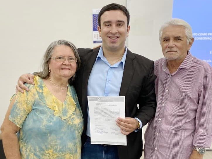 Antoniel Holanda segura um documento entre a mãe e um senhor