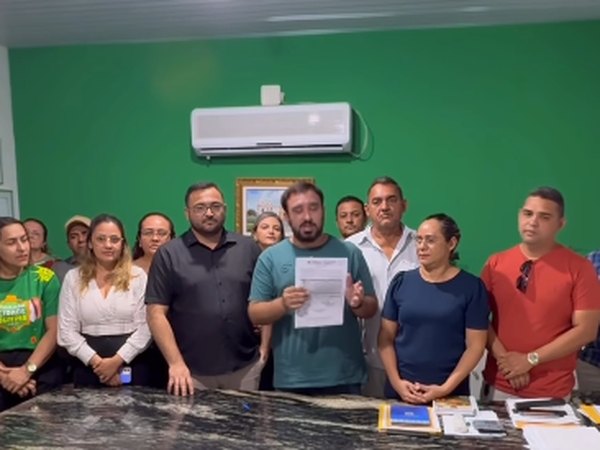 Antoniel Holanda mostra documento assinado, ao lado de equipe, em sala de paredes verdes